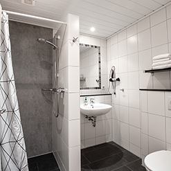 Badezimmer mit Dusche, Waschbecken und WC im Doppelzimmer mit Küche